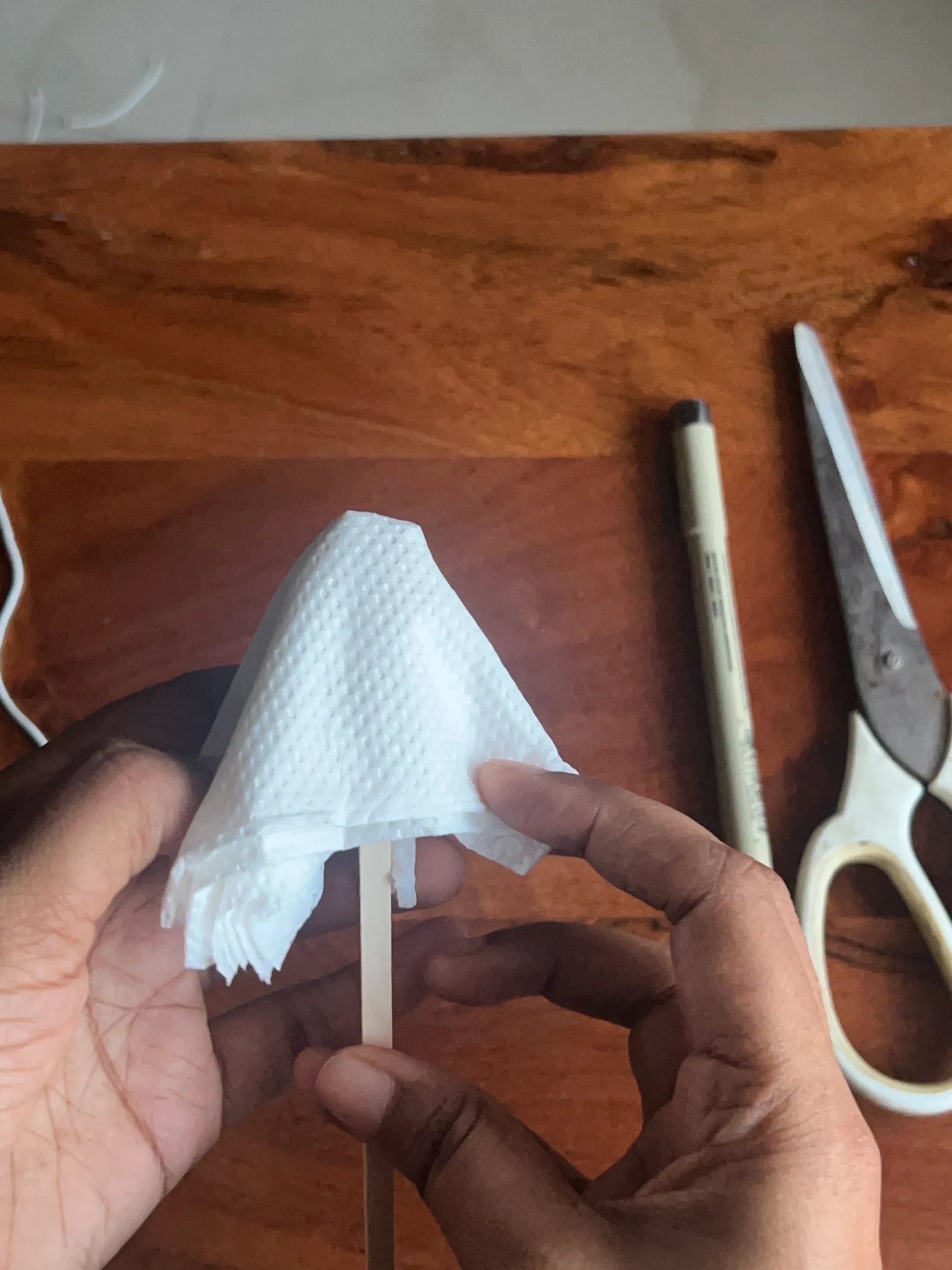 Gathering tissue paper around a stick to make a Halloween ghost