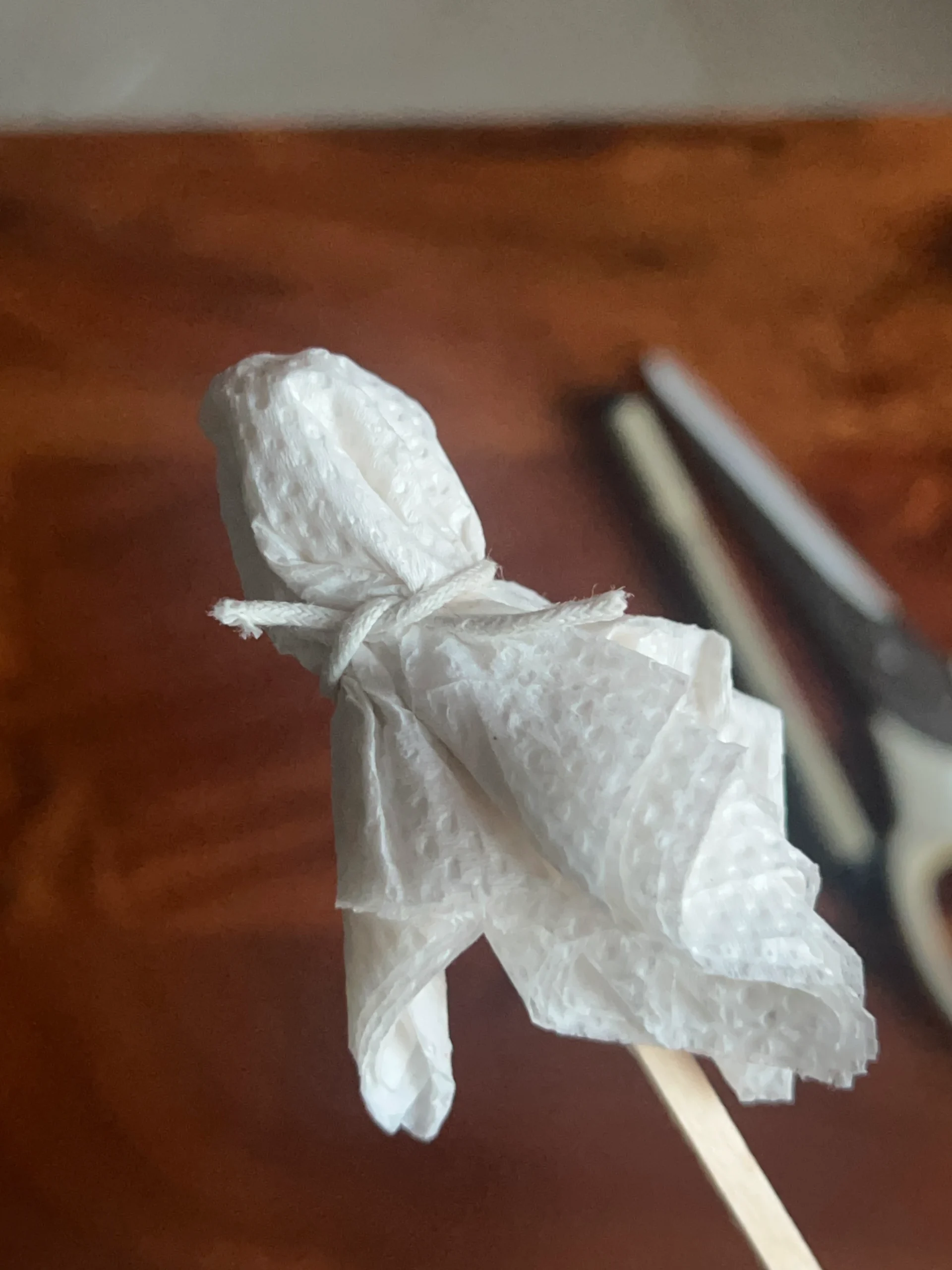 Tying thread around tissue paper to secure the Halloween ghost shape.